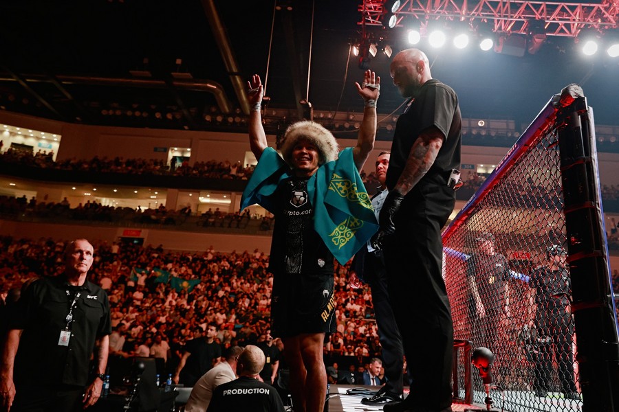 Asu Almabayev celebrates his win outside of the octagon cage and raises his hand to the crowd