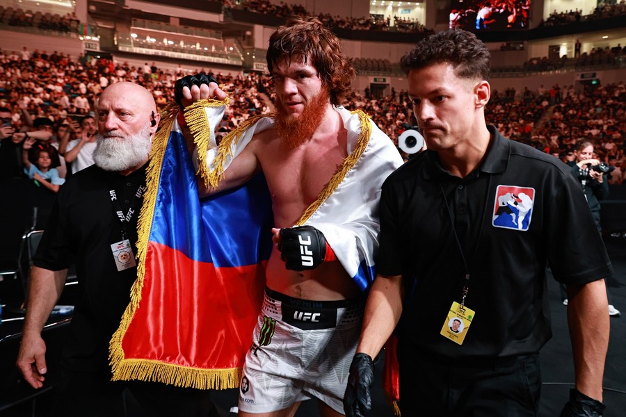 Shara Magomedov leaves the octagon while passing near fans while carrying the Russian flag